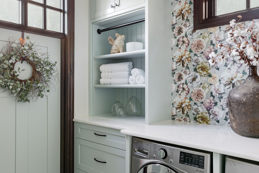 A stylish laundry room featuring floral wallpaper, modern appliances, and encaustic patterned tile flooring undergoes a renovation by a prominent Calgary interior designer.