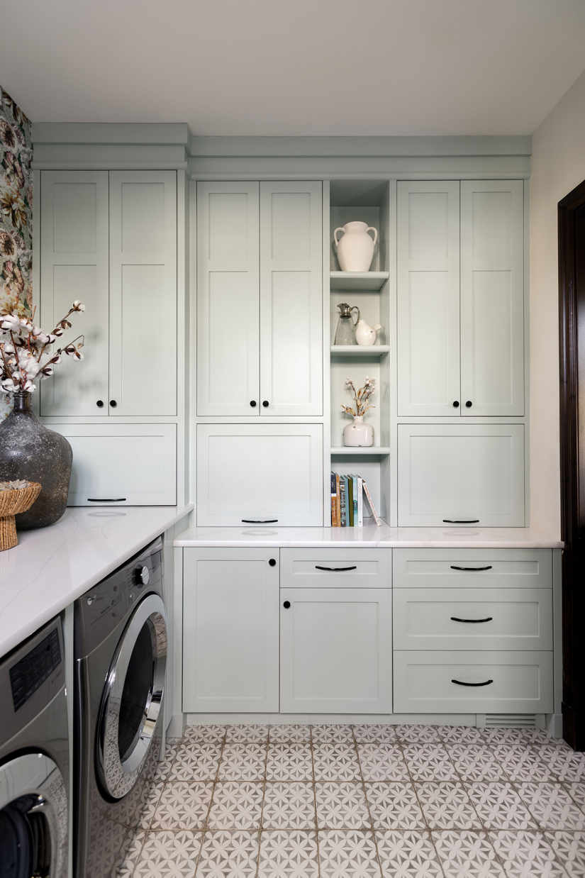 A stylish laundry room featuring floral wallpaper, modern appliances, and encaustic patterned tile flooring undergoes a renovation by a prominent Calgary interior designer.