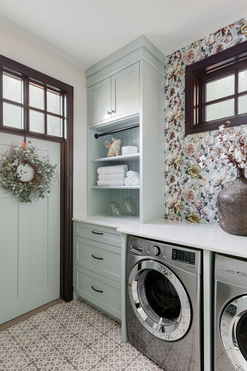 A stylish laundry room featuring floral wallpaper, modern appliances, and encaustic patterned tile flooring undergoes a renovation by a prominent Calgary interior designer.