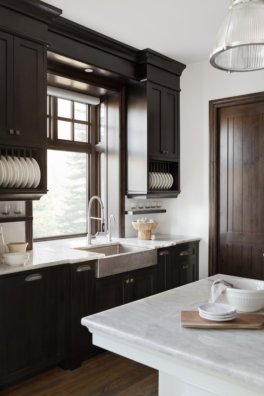 Elegant kitchen with a central island, dark wood cabinets, and stone range hood, designed by a renowned New Home Designer in Calgary.