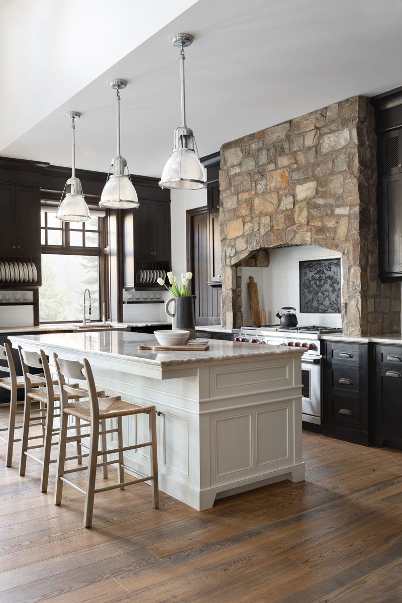 Elegant kitchen with a central island, dark wood cabinets, and stone range hood, designed by a renowned New Home Designer in Calgary.