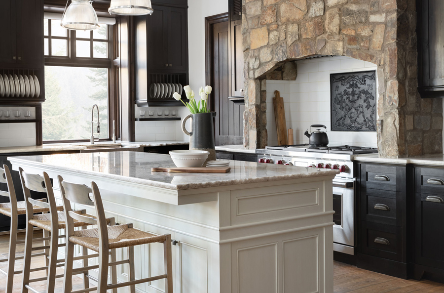 Elegant kitchen with a central island, dark wood cabinets, and stone range hood, designed by a renowned New Home Designer in Calgary.