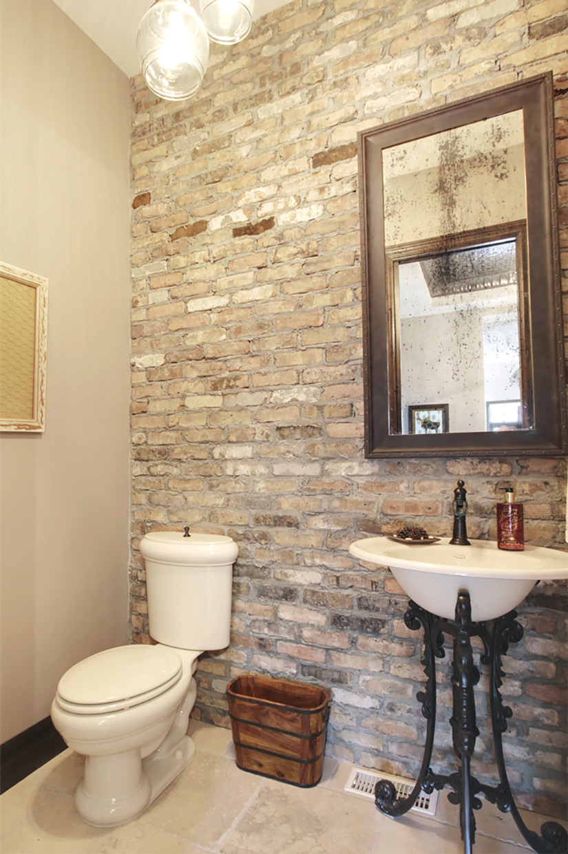 Elegant industrial exposed brick wall powder room bathroom by a renowned New Home Designer in Calgary.