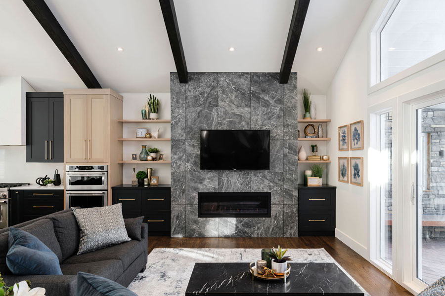 Modern living room with a grey marble fireplace, white walls with dark beams, built-in shelves, and elegant decor.