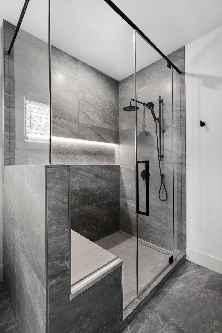 Modern bathroom renovation with gray marble tiles and glass shower enclosure, designed by a top Calgary interior designer.