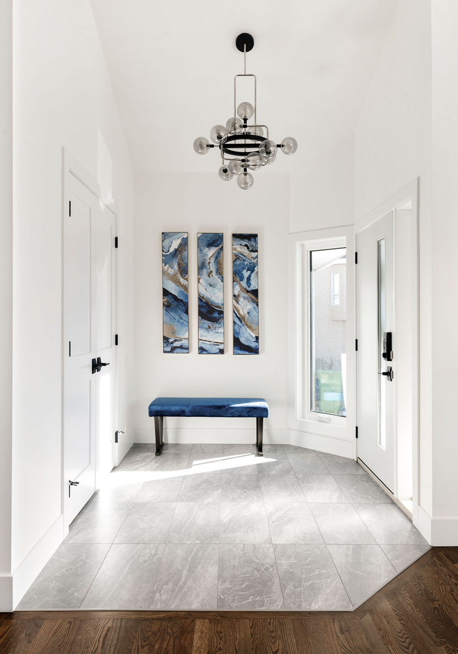 Modern bright foyer renovation with black accents, pendant lighting, and a view into an adjacent living area, designed by a top Calgary interior designer.