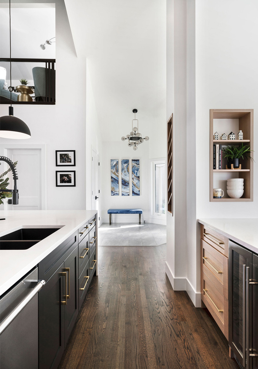 Modern kitchen with black accents, pendant lighting, and a view into an adjacent living area, designed by a top Calgary interior designer.