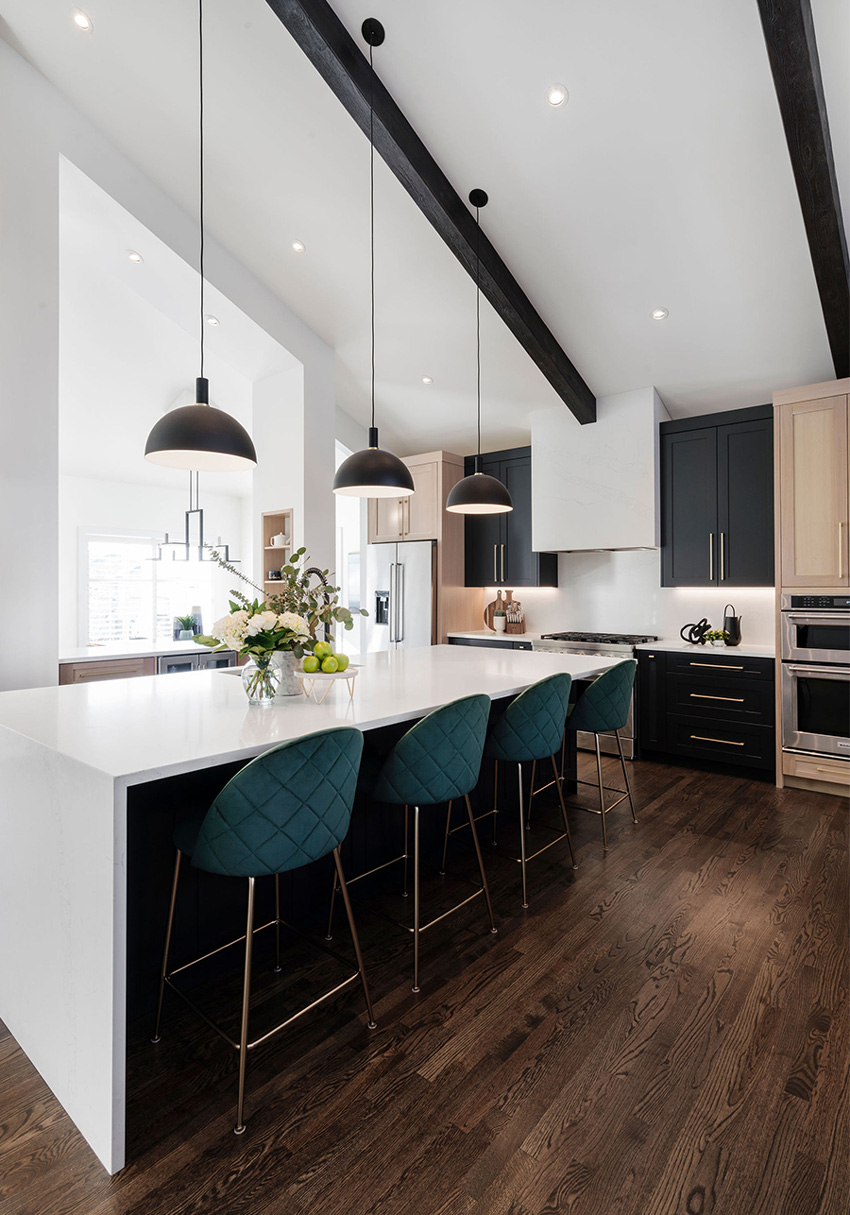 Modern kitchen with black accents, pendant lighting, and a view into an adjacent living area, designed by a top Calgary interior designer.