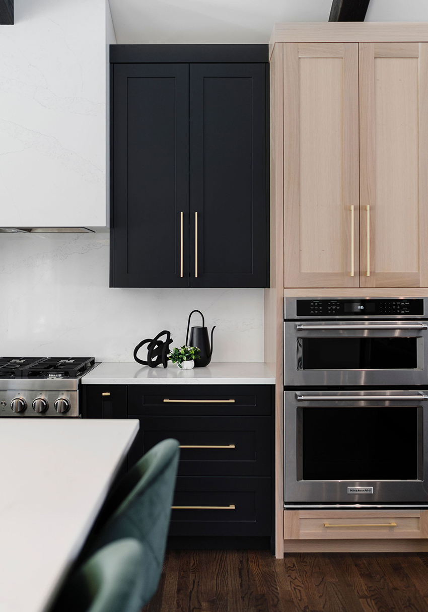 Modern kitchen with black accents, pendant lighting, and a view into an adjacent living area, designed by a top Calgary interior designer.