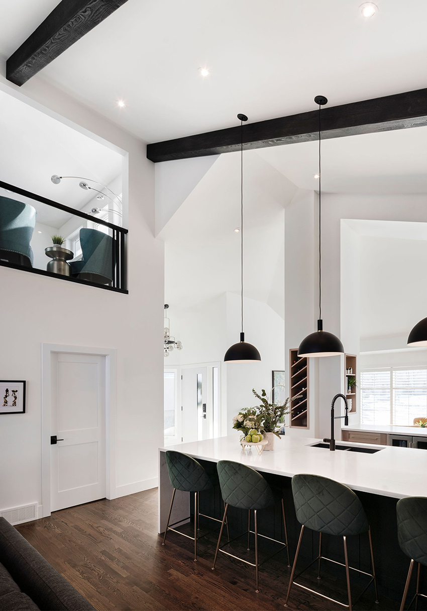 Modern kitchen with black accents, pendant lighting, and a view into an adjacent living area, designed by a top Calgary interior designer.