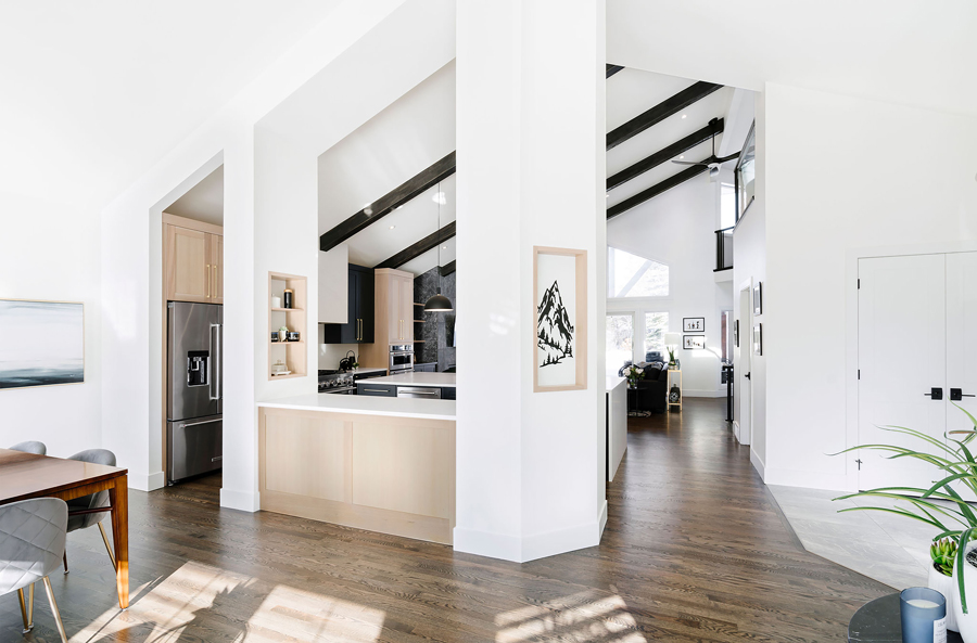 Modern kitchen with black accents, pendant lighting, and a view into an adjacent living area, designed by a top Calgary interior designer.