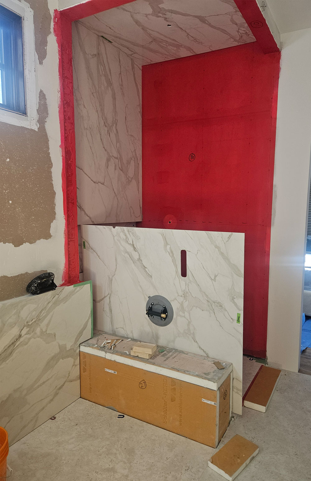 Ensuite renovation in progress showing shower waterproofing, large-format marble-look porcelain slab installation and construction of the integrated shower bench.